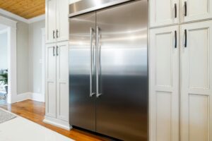 Sleek stainless steel refrigerator amidst elegant cabinetry in a bright kitchen.
